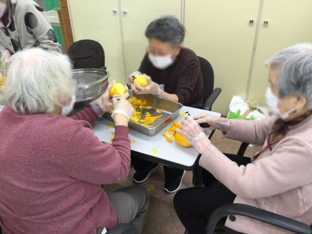 料理作業をする人々の居室 居室 テーブルを囲んで料理を楽しむ様子です。和やかな雰囲気の中で、軽作業が行われています。