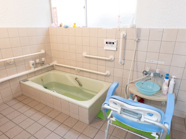 手すり付き洗面所と浴槽 浴室 安全性を考慮した設計の浴室です。手すりやシャワーチェアが整えられ、利用者の快適な入浴を支援しています。