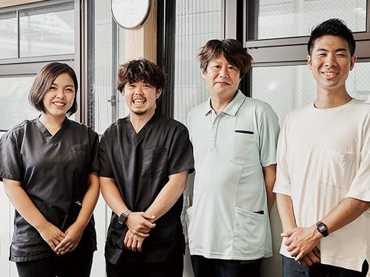 スタッフ4人が並ぶ外観前  