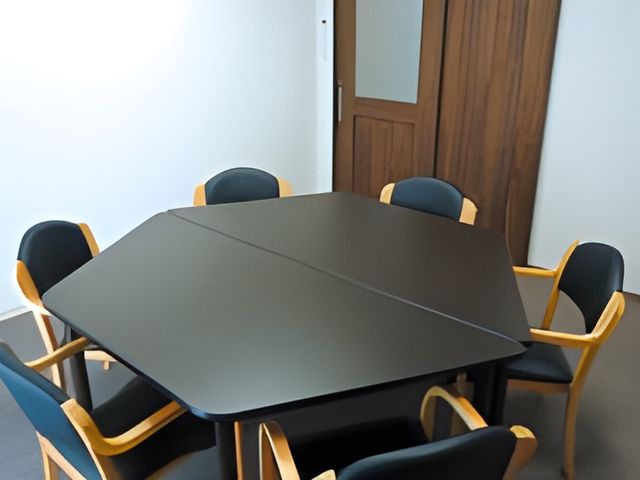 六角形のテーブルの部屋 多目的室 静かな環境でグループミーティングや趣味の活動ができる場所です。自然な木目のテーブルが特徴です。