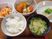 白いご飯に味噌汁、野菜の煮ものに揚げ物、冷ややっこなどが並べられ、手前には箸が置かれている。