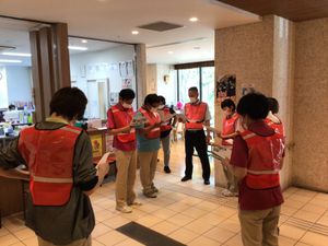 赤いベストの職員が集まるロビー  