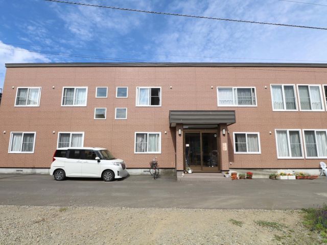 茶色い外壁の建物エントランス 外観 広々とした入り口が印象的な建物です。明るい色合いで心地良い雰囲気を感じさせるデザインとなっております。