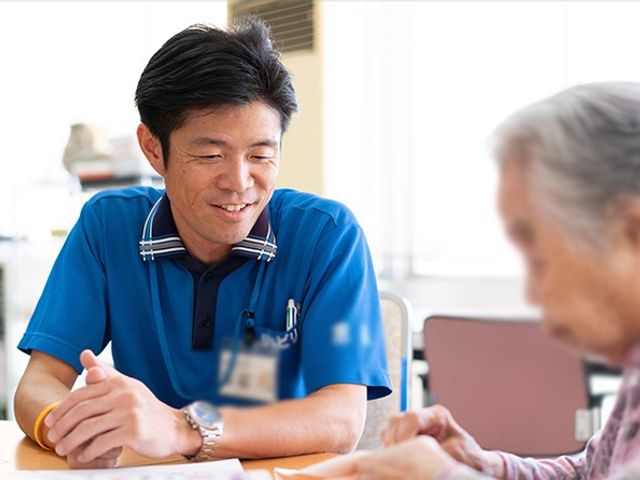 対話する様子 スタッフイメージ スタッフと入居者が和やかに談話しており、温かいサポート環境が伺えます。