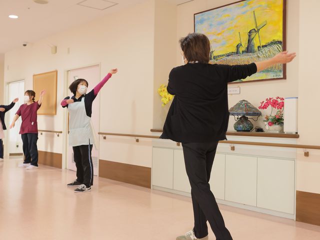 運動を楽しむ人たちの廊下 廊下 幅広い廊下で、スタッフと利用者が楽しく体操をしています。明るい絵画も飾られています。
