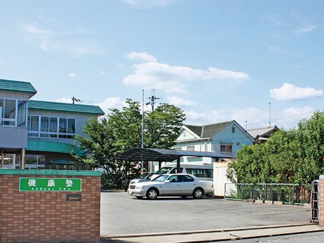 施設の外観 外観   青空の下に建物と駐車スペースが見える、落ち着いた雰囲気の外観です。正面には看板があり、来訪時の目印になりそうです。