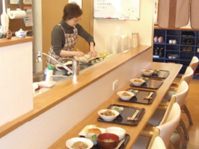 料理が並ぶキッチン キッチン 料理が並ぶカウンターで、スタッフが軽やかに準備を進めています。暖かな雰囲気です。