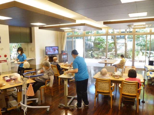 庭に面するラウンジ ラウンジ 自然光が心地よく降り注ぐ広々としたスペースで、利用者の方々がくつろいでいます。