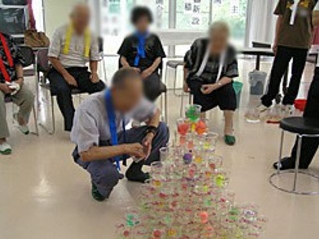 積み重ねられたカップ 多目的室 カラフルなカップタワーを囲む集まりです。リラックスした雰囲気の中で交流できます。
