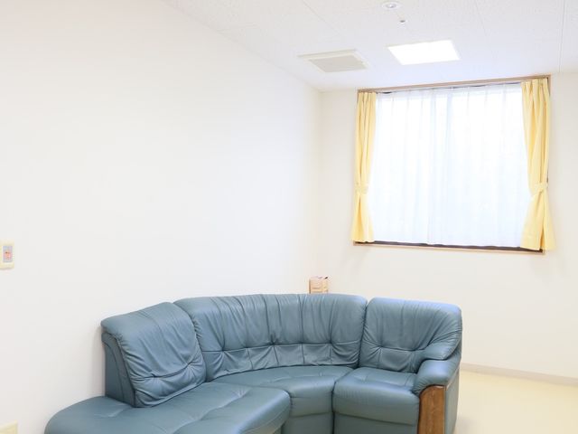 清潔な居室の一角 休憩スペース 採光豊かなこの居室には、ゆったりとくつろげる青いリクライニングチェアが備えられており、居心地の良い空間が提供されています。