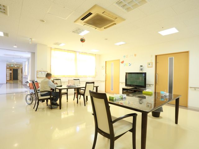 共有スペースの明るい居室 共有スペース ゆとりあるラウンジでは、テーブルを囲みながらゆったりと過ごす方の様子が見られます。明るく開放的な雰囲気で、ご自由におくつろぎいただける空間です。