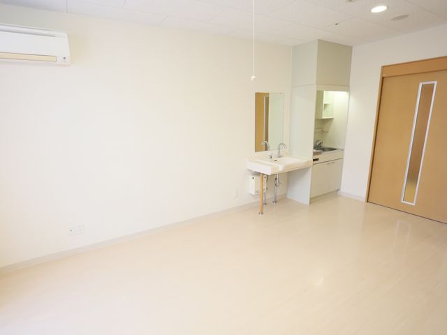 明るい居室の一角 居室 広々とした居室には、洗面所が設けられ、日々の生活がしやすく配慮されています。窓からの自然光が明るく心地よい空間を演出しています。