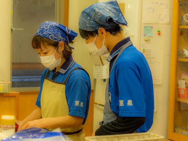 スタッフが作業する姿 同じ目的に向かって協力し合うスタッフの姿は、温かな職場環境を感じさせます。お互いを思いやる心が、ここには流れています。