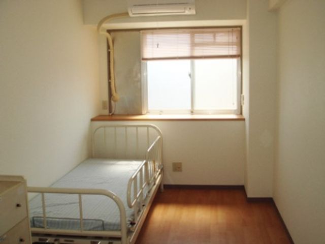 明るい個室の一角 居室 窓から自然光が差し込む快適な居室です。シンプルな家具が配置され、落ち着いた雰囲気があります。