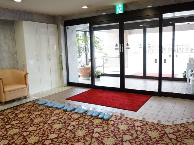 エントランスの明るい空間 玄関 エントランスは開放感があり、待合には柔らかな色合いのソファが備え置かれています。スリッパが並べられ、訪れた方々を優しく迎え入れる構えです。