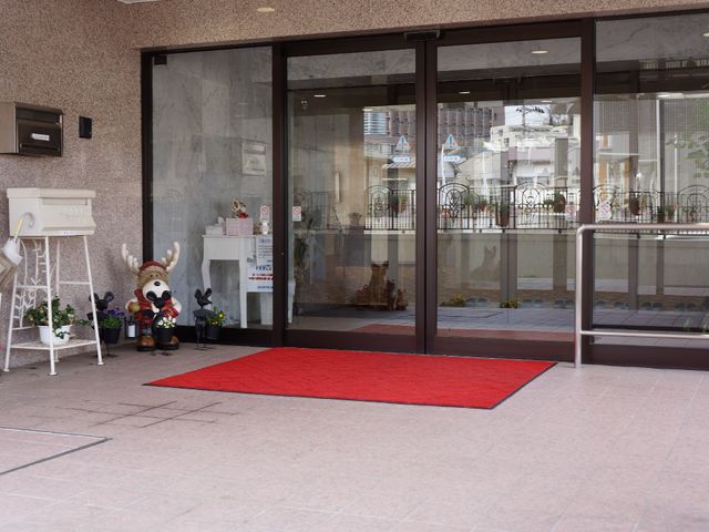 エントランスの装飾と赤いカーペット 施設出入り口 アクセントとなる赤いカーペットが敷かれたエントランスは、明るく開放的な印象を与えます。キャラクターの置物が心温まる歓迎の雰囲気を演出しています。