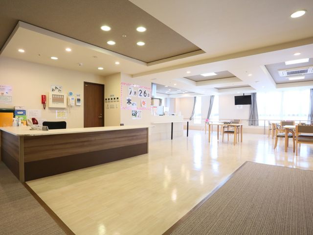 共用スペースの明るい室内 食堂 広々とした開放感のあるロビーです。快適にご利用いただけるよう、テーブル席や受付カウンターが整えられています。