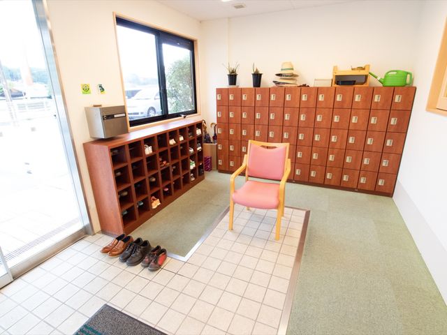 エントランスに置かれた靴箱 玄関 きれいに整理された靴箱と、待合に配置された椅子が訪れた方を温かく迎えます。明るい日差しの入るエントランスは開放感があります。