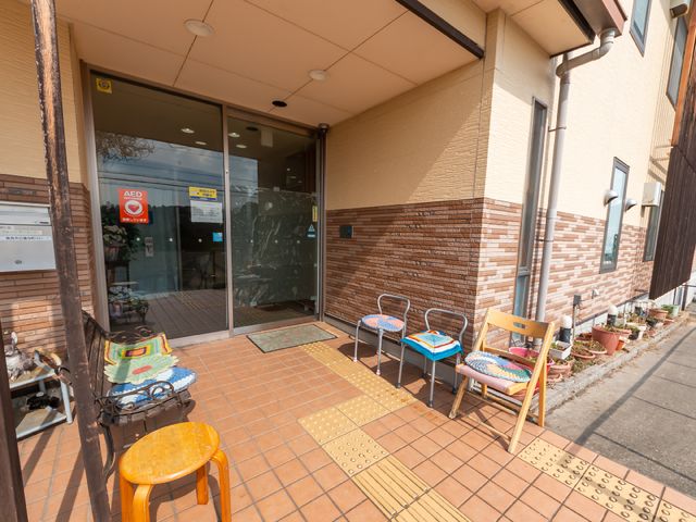 入り口とベンチ 玄関 ガラス扉のエントランスにはベンチが並び、歓迎するような雰囲気を醸し出しています。職員や訪問者の交流の場としても利用できそうです。