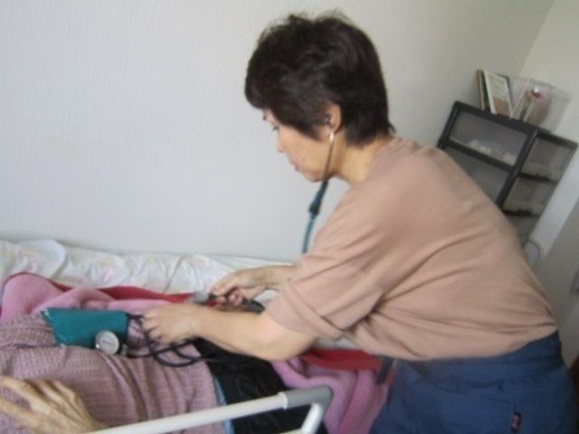看護師の活動居室 居室 看護スタッフが血圧を測定しています。温かみのある対応で安心できる環境が整っています。