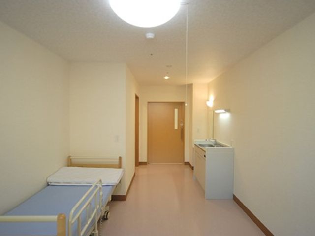 清潔な個室の一室 居室 シンプルで清潔感のある居室です。ベッドと小さなキッチンが備わり、快適な個人のスペースを提供しています。