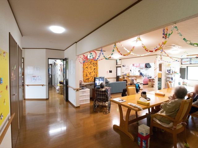 広々とした共有スペース リビング ゆったりとした座席と明るい飾り付けが印象的な共有スペースです。利用者の方々がくつろいでいる様子が伺えます。