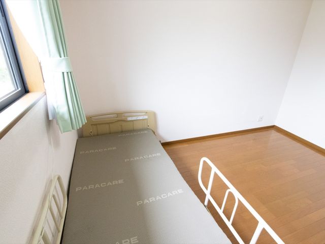 居室のベッドと窓 居室 シンプルで清潔感のある居室です。木目調のフロアが温もりを感じさせ、ゆったりと落ち着いた時間を過ごせます。
