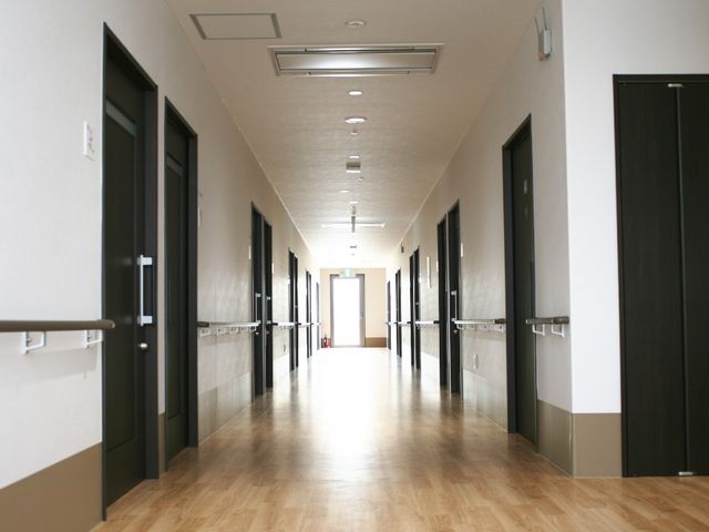 明るい廊下 廊下   手すりが両側に設けられた、まっすぐ伸びる明るい廊下です。各居室の出入りがしやすそうな落ち着いたつくりです。