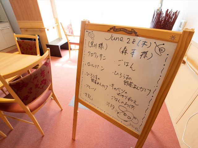 活動予定の記載されたボード 食堂 活動の予定が記されたボードが置かれている温かみのある空間です。共に過ごす時間が充実している様子が伺えます。