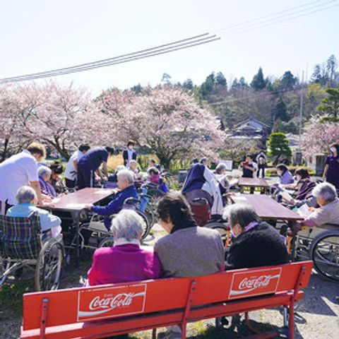 花見を楽しむ庭 庭 桜の下で多くの方が集まり、リラックスしたひとときを過ごせます。介護職員も一緒に活動しています。