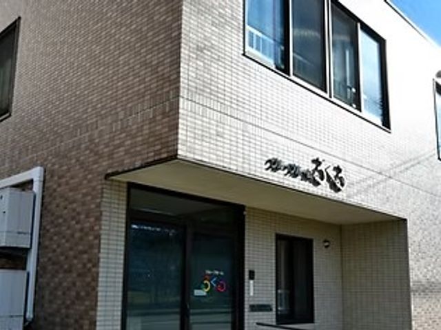 施設外観の建物正面 外観   落ち着いた色合いの外壁に、すっきりした印象の出入口がある建物です。看板も見え、訪れる方にわかりやすい外観です。