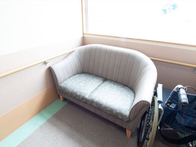 待合室のソファと車椅子 通路 明るく落ち着いた雰囲気の待合室には、くつろげるソファが設置されており、訪れる方々を温かく迎えています。