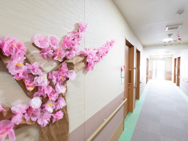 桜飾り付けのある廊下 通路 廊下に桜の装飾が施され、春の訪れを彩っています。落ち着いた色合いで統一された空間が、訪れる方々に安らぎを与えています。