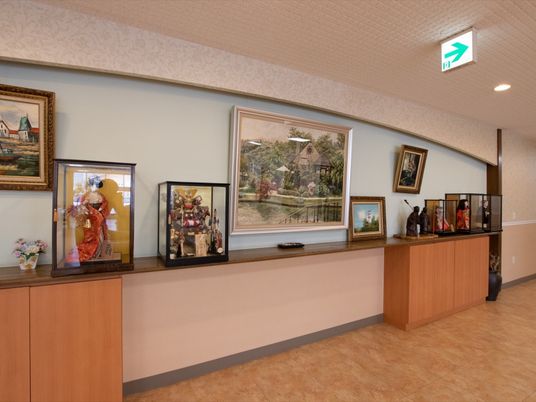 共有スペースの棚には、ガラスのケースに収められた日本人形が何体か置かれている。壁には大きいサイズの風景画が飾られている。