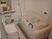 白を基調とした浴室の空間は、清潔感に溢れている。洗い場の鏡の下に２段の棚を設け、上にシャンプーやソープ、下に洗面器を置いている。