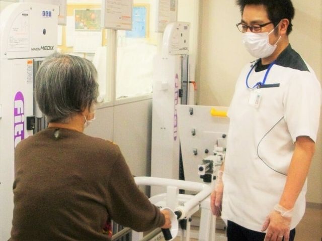 新人向け施設案内の訓練室 機能訓練室 利用者が専属スタッフと共に訓練設備でリハビリを行っています。職場の雰囲気を感じられます。