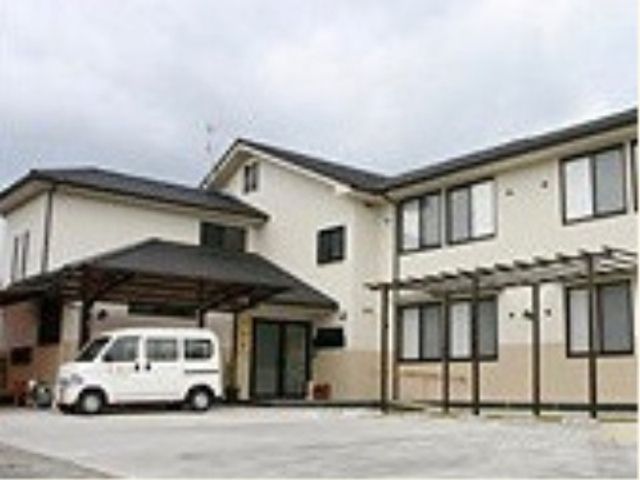 白い車が停まった建物外観 外観 広々とした敷地に建つ、ゆとりある外観の建物です。落ち着いた色合いで、来訪者を温かく迎えます。