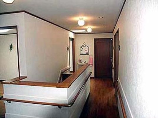 階段を上がった2階の廊下である。廊下の両側の壁には手すりが付いている。一般家庭のようなアットホームな雰囲気である。