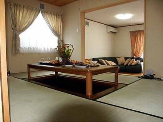 洋室と和室が一つながりになっている。和室には大きめの掘りごたつがあり、洋室には大きなソファが置かれている。