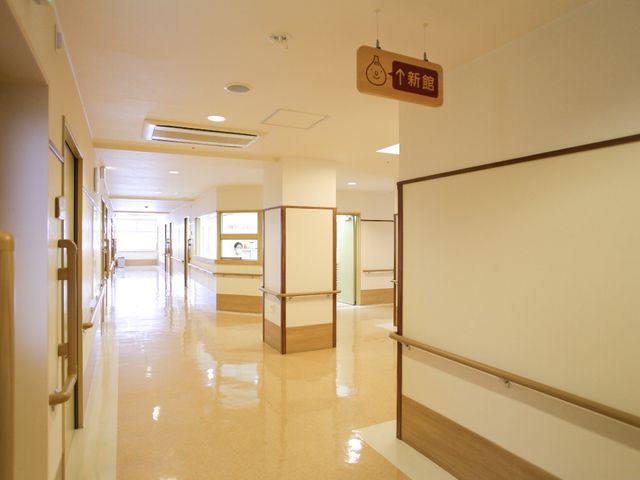 明るく清潔な廊下 渡り廊下 床はつややかで、手すりも設置された安全に配慮された廊下です。スタッフの作業効率も考慮した設計で、ゆったりとしたスペースが確保されています。