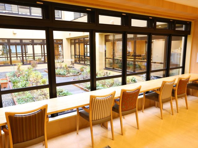 快適な中庭の眺望 食堂 温かみのある木目調のラウンジです。大きな窓から自然光が差し込み、中庭の緑をご覧いただけます。