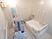明るい浴室の奥の壁はベージュ色と淡い灰色で構成されている。モザイク柄になっておりデザイン性のある空間となっている。