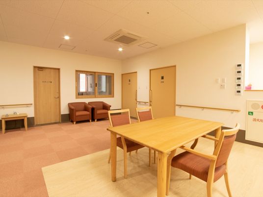 スタッフ室の前には一人掛けのソファが二脚置かれている。ホールの中央にはダイニングテーブルと椅子がセットで用意されている。