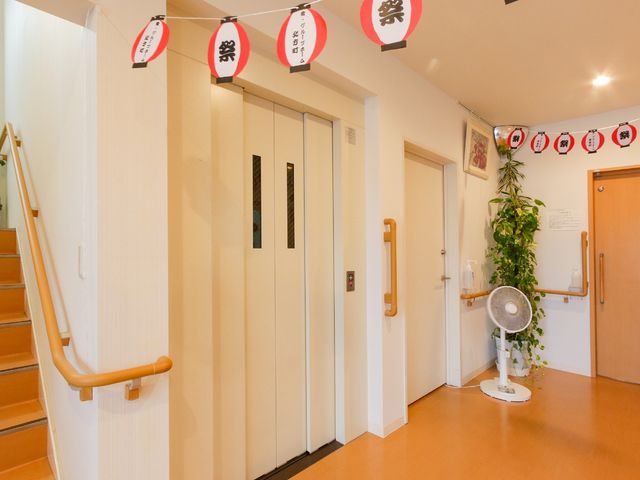 和やかなエレベーターホール エレベーター 手すりを設けた廊下には、趣のある提灯が飾られており、温かみのある雰囲気を感じられます。安全かつ快適な空間作りに配慮されています。