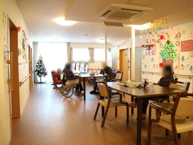 暖かみのあるダイニングルーム 食堂 季節の装飾が施されたダイニングで、利用者がゆったりとくつろいでいます。木のテーブルや椅子が温かな雰囲気を演出しています。
