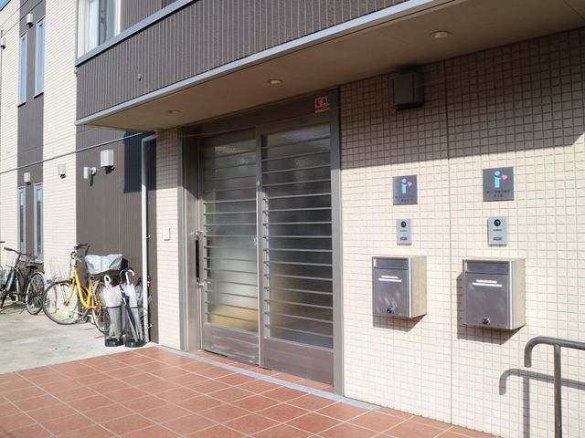 エントランスと自転車置き場 玄関 清潔感あふれるエントランスは、スタッフや来訪者が毎日出入りする顔です。明るいタイルが迎える心地よい空間です。
