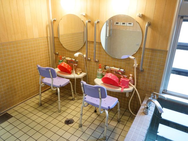 バリアフリー設計の洗面所 かわいい備品 安全に配慮された浴室内の洗面スペースです。手すり付きのシートで、安心してご利用いただけます。