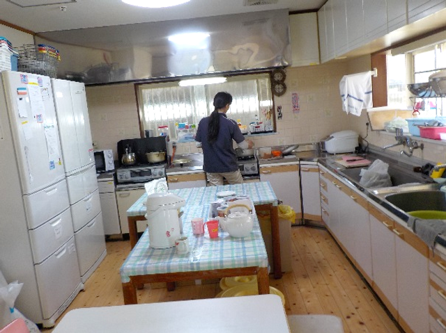 調理中の様子キッチン キッチン 自然光が差し込むキッチンで、スタッフが調理をしています。広い作業台が特徴です。