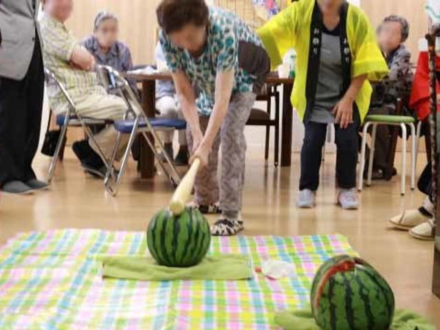 多世代交流イベント スイカ割り 利用者同士の和やかな交流を促すイベントが広々とした多目的室で行われています。笑顔があふれる温かい雰囲気が伝わります。