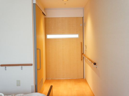 居室の扉は車椅子利用者も出入りしやすい大型の引き戸。ベッド周りの壁にも手すりがつけられている。